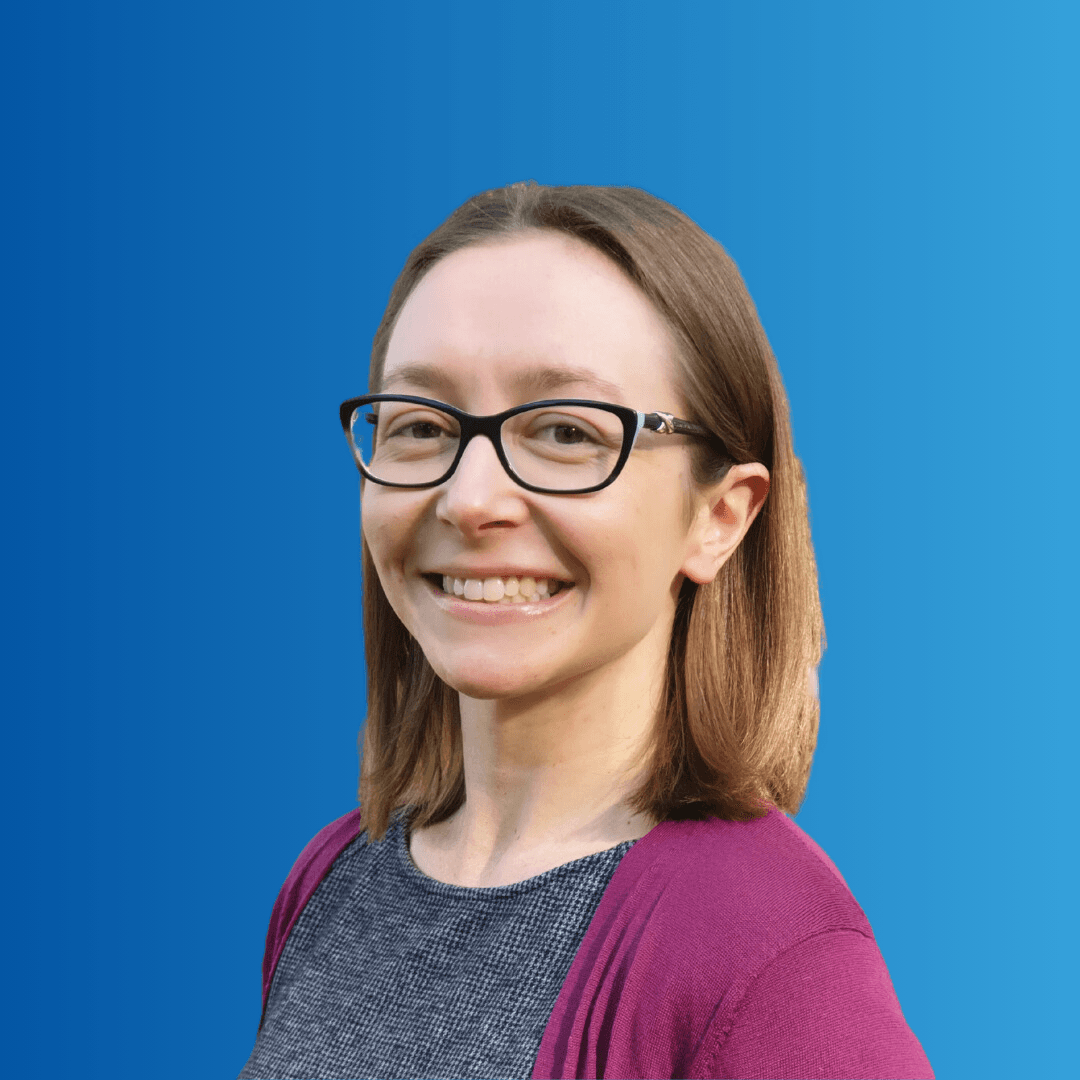 A woman in glasses smiling at the camera on a blue background